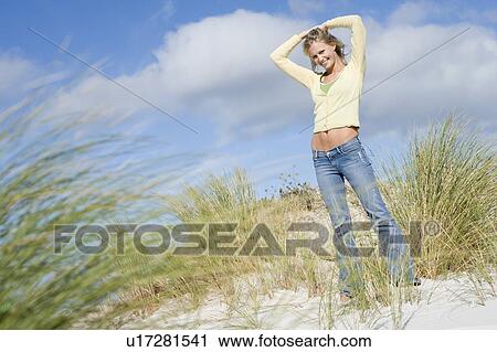 Young woman posing on a sand hill View Large Photo Image Stock Image - Young woman posing on a sand hill. Fotosearch