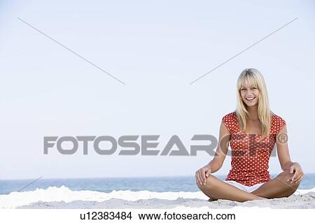Picture - Young woman sitting on a beach. Fotosearch