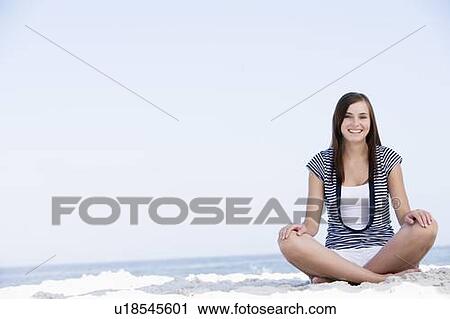 Young woman sitting on a beach View Large Photo Image Stock Image - Young woman sitting on a beach. Fotosearch