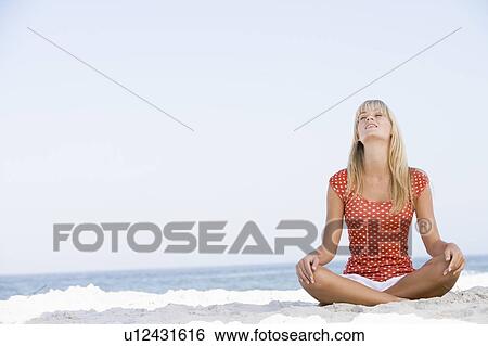 Young woman sitting on a beach View Large Photo Image Stock Photograph - Young woman sitting on a beach. Fotosearch