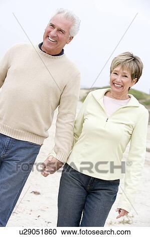 Couple at the beach holding hands and smiling View Large Photo Image Stock Image - Couple at the beach holding hands and smiling. Fotosearch