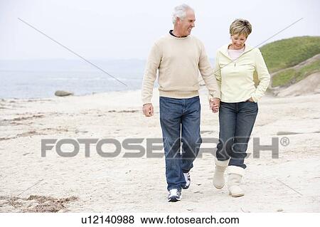 Couple at the beach holding hands and smiling View Large Photo Image Stock Photo - Couple at the beach holding hands and smiling. Fotosearch