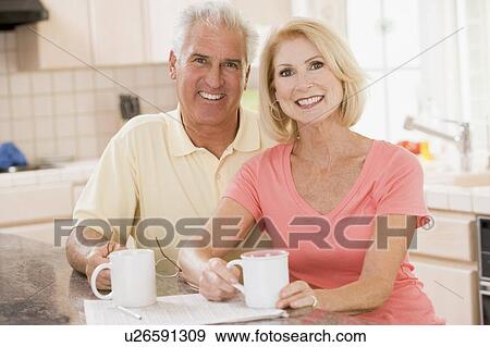 Stock Photo - Couple in kitchen with coffee smiling. Fotosearch