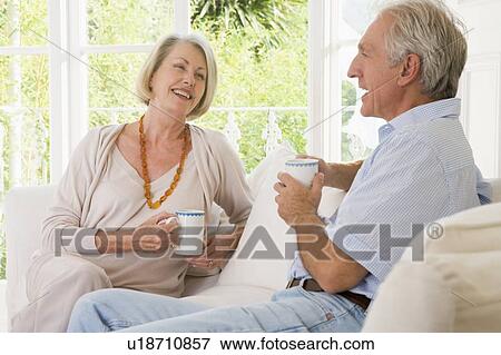 Couple in living room with coffee smiling View Large Photo Image Stock Photo - Couple in living room with coffee smiling. Fotosearch