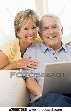 Couple in living room with laptop smiling View Large Photo Image Stock Photograph - Couple in living room with laptop smiling. Fotosearch