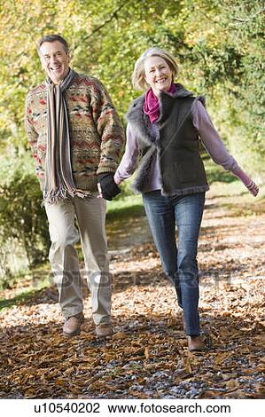 Couple outdoors running on path in park holding hands and smiling (selective focus) View Large Photo Image Stock Image - Couple outdoors running on path in park holding hands and smiling (selective focus). Fotosearch