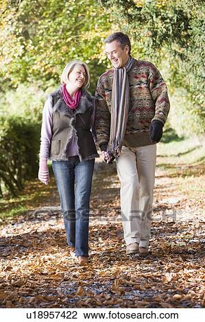 Couple outdoors walking on path in park holding hands and smiling (selective focus) View Large Photo Image Stock Image - Couple outdoors walking on path in park holding hands and smiling (selective focus). Fotosearch