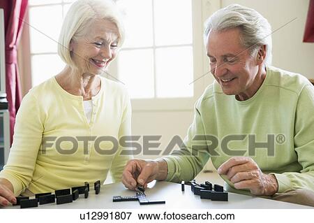 Stock Photo - Couple playing dominos in living room smiling. Fotosearch