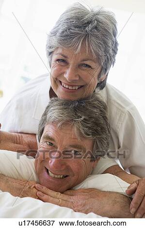 Couple relaxing in bedroom and smiling View Large Photo Image Stock Photo - Couple relaxing in bedroom and smiling. Fotosearch