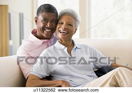 Stock Image - Couple relaxing in living room and smiling. Fotosearch