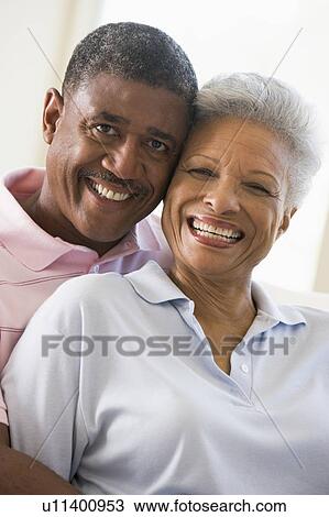 Stock Image - Couple relaxing in living room and smiling. Fotosearch