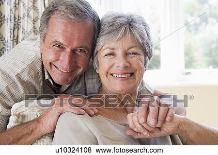 Stock Photo - Couple relaxing in living room smiling. Fotosearch