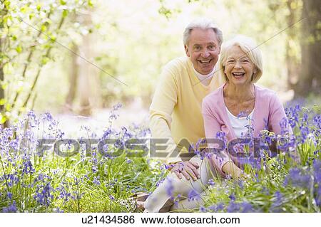 Couple sitting outdoors with flowers smiling View Large Photo Image Stock Photograph - Couple sitting outdoors with flowers smiling. Fotosearch