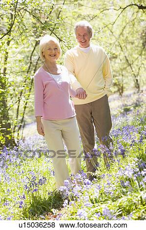 Couple walking outdoors holding hands smiling View Large Photo Image Stock Photo - Couple walking outdoors holding hands smiling. Fotosearch