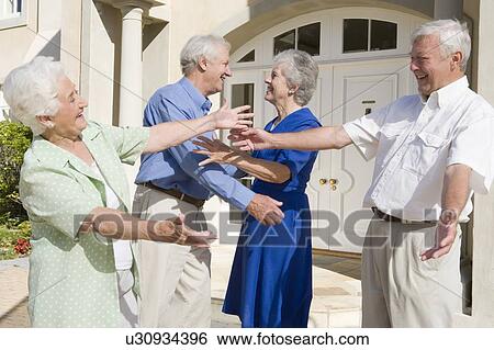 Stock Photograph - Two senior couples greeting each other with open arms. Fotosearch