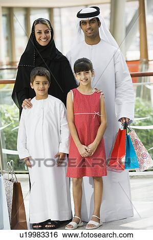 Stock Photograph - Family standing in mall smiling (selective focus). Fotosearch