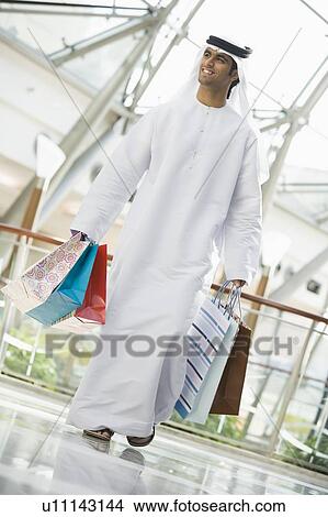 Picture - Man walking in mall smiling (selective focus). Fotosearch