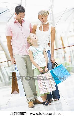 Stock Image - Mother and father with young daughter at a shopping mall. Fotosearch