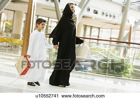 Woman and young boy walking in mall smiling (selective focus) View Large Photo Image Stock Image - Woman and young boy walking in mall smiling (selective focus). Fotosearch