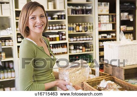 Stock Image - Woman in market looking at bread smiling. Fotosearch