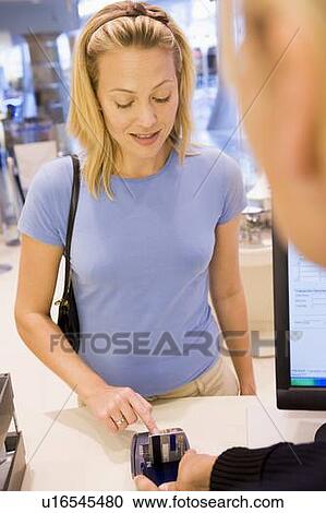 Stock Image - Woman paying for purchases with credit card. Fotosearch