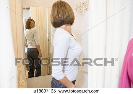 Stock Photography - Woman trying on jeans and frowning. Fotosearch