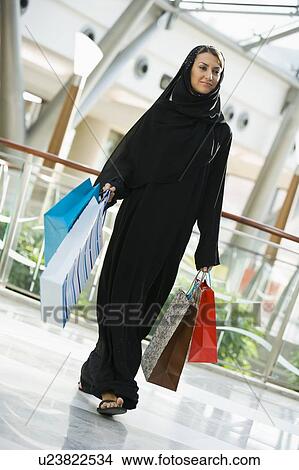 Woman walking in mall smiling (selective focus) View Large Photo Image Picture - Woman walking in mall smiling (selective focus). Fotosearch