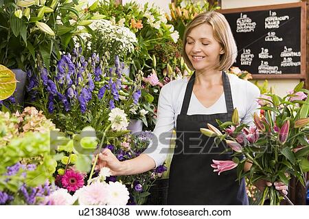 Stock Photo - Woman working at flower shop smiling. Fotosearch