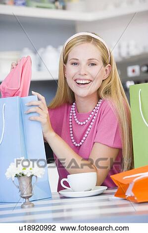 Young woman sitting at a table taking a break from shopping View Large Photo Image Stock Image - Young woman sitting at a table taking a break from shopping. Fotosearch