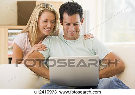 Couple in living room using laptop smiling View Large Photo Image Stock Image - Couple in living room using laptop smiling. Fotosearch