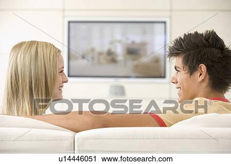 Stock Image - Couple in living room watching television smiling. Fotosearch