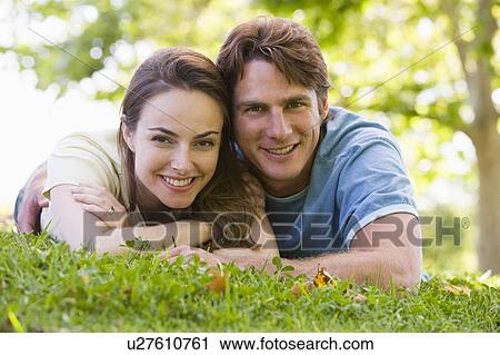 Stock Image - Couple lying outdoors smiling. Fotosearch