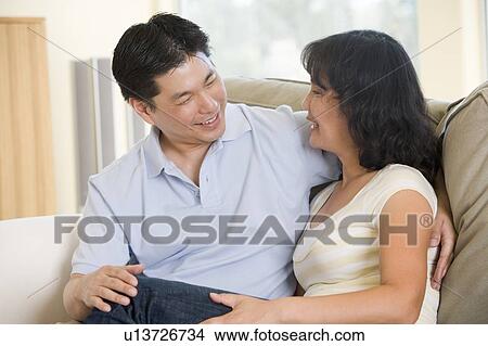 Picture - Couple relaxing in living room talking and smiling. Fotosearch