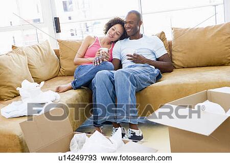 Couple relaxing with coffee by boxes in new home smiling View Large Photo Image Stock Image - Couple relaxing with coffee by boxes in new home smiling. Fotosearch