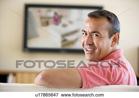 Man in living room watching television smiling View Large Photo Image Stock Photo - Man in living room watching television smiling. Fotosearch