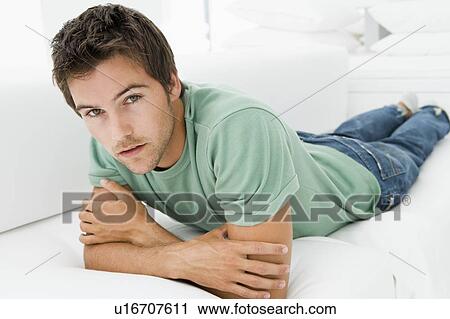 Stock Image - Man lying in living room. Fotosearch