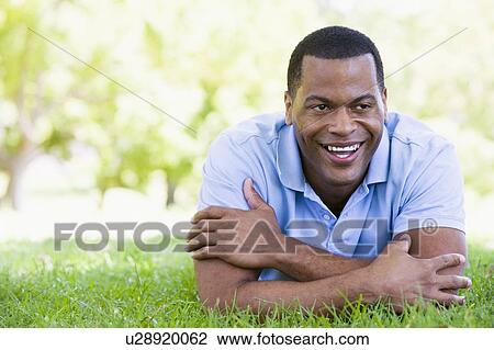 Man lying outdoors smiling View Large Photo Image Stock Image - Man lying outdoors smiling. Fotosearch