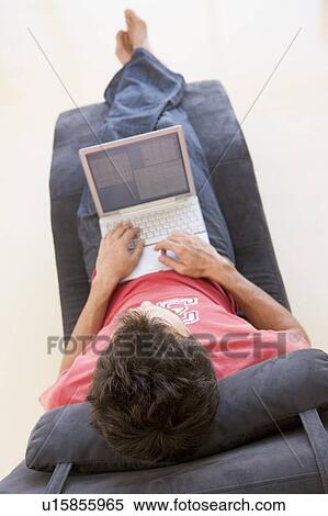 Stock Photography - Man sitting in chair using laptop. Fotosearch