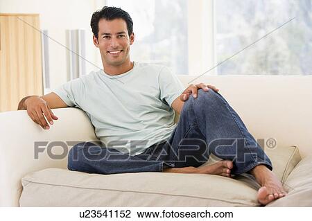 Man sitting in living room smiling View Large Photo Image Stock Image - Man sitting in living room smiling. Fotosearch