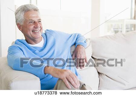 Man sitting in living room smiling View Large Photo Image Stock Photo - Man sitting in living room smiling. Fotosearch