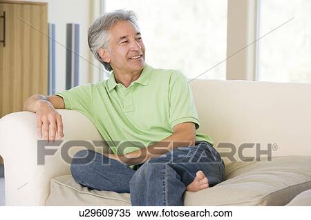 Man sitting in living room smiling View Large Photo Image Stock Photography - Man sitting in living room smiling. Fotosearch