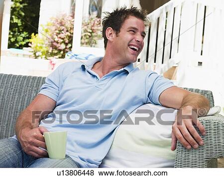 Man sitting on patio with coffee laughing View Large Photo Image Stock Photo - Man sitting on patio with coffee laughing. Fotosearch