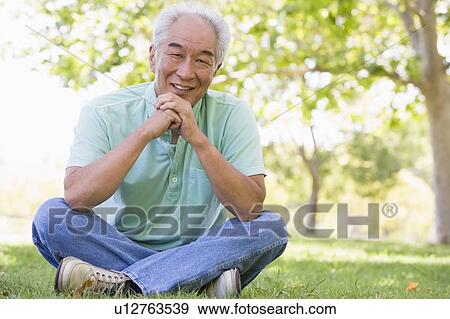 Man sitting outdoors smiling View Large Photo Image Stock Photo - Man sitting outdoors smiling. Fotosearch