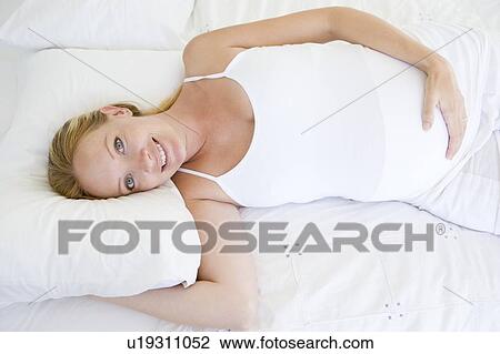 Pregnant woman lying in bed smiling View Large Photo Image Stock Image - Pregnant woman lying in bed smiling. Fotosearch