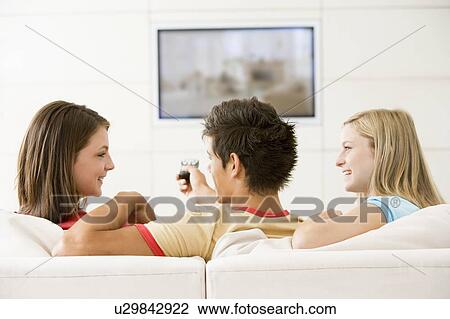 Three friends in living room watching television smiling View Large Photo Image Stock Image - Three friends in living room watching television smiling. Fotosearch