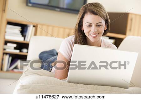 Woman in living room using laptop smiling View Large Photo Image Stock Photo - Woman in living room using laptop smiling. Fotosearch