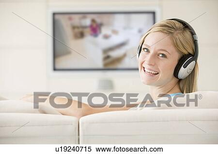 Woman in living room watching television and wearing headphones smiling View Large Photo Image Stock Photography - Woman in living room watching television and wearing headphones smiling. Fotosearch