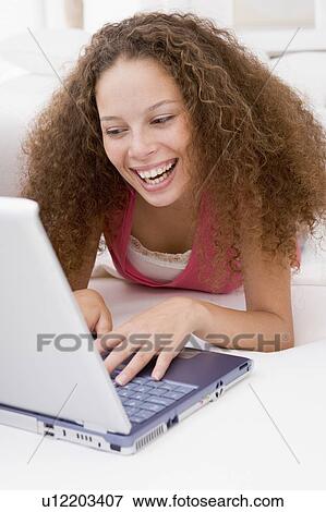 Woman lying in bed with laptop smiling View Large Photo Image Stock Photo - Woman lying in bed with laptop smiling. Fotosearch