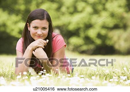 Stock Photograph - Woman lying outdoors with flower smiling. Fotosearch