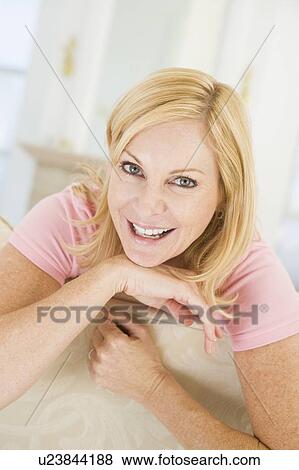 Woman sitting in living room smiling View Large Photo Image Stock Photo - Woman sitting in living room smiling. Fotosearch